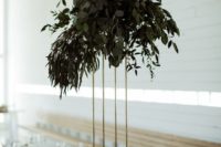 11 a tall minimalist wedding centerpiece on a gilded stand and with lush textural greenery won’t take much table space
