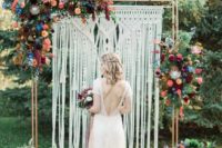 12 a macrame wedding backdrop with bright orange, burgunyd, peachy pink and blue flowers plus greenery
