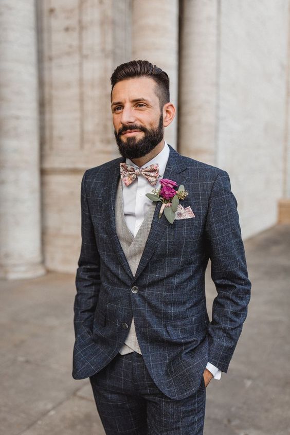 a graphite grey checked suit, a grey waistcoat, a white shirt and a printed floral bow tie plus a matching handkerchief