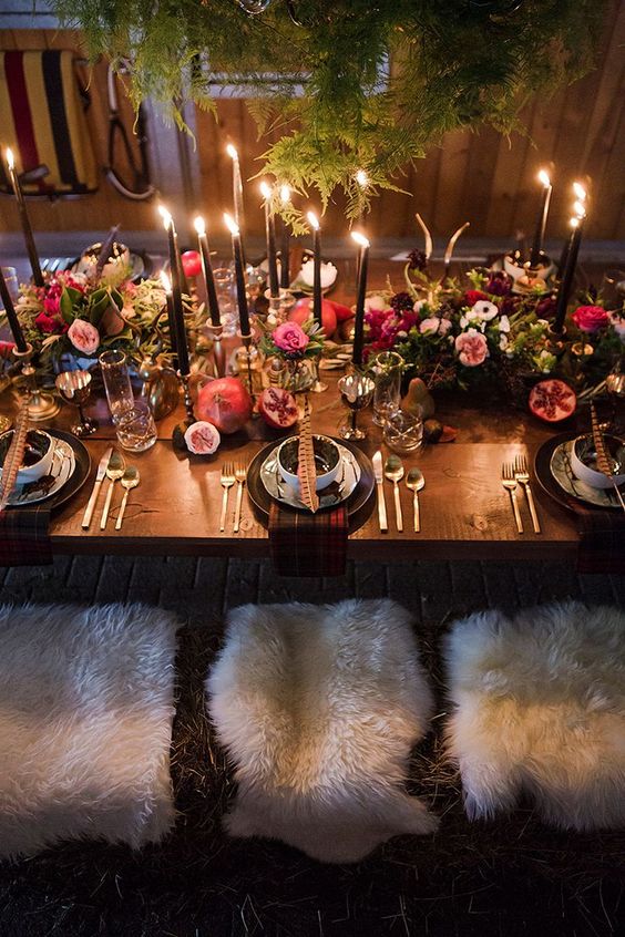 a refined wedding tablescape with ferns hanging over it, black candles, lush moody florals, feathers and pomegranates
