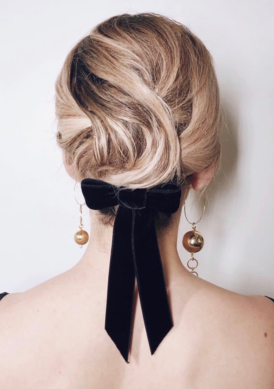 a wavy short hairstyle highlighted with a black velvet ribbon bow and statement mismatching earrings