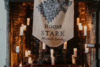 15 a unique wedding backdrop with a fireplace with candles, a velvet seat and a Stark flag