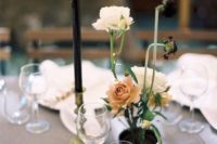 16 a delicate floral arrangement of a black vase, white and dusty pink blooms and a black candles in a gold candle holder