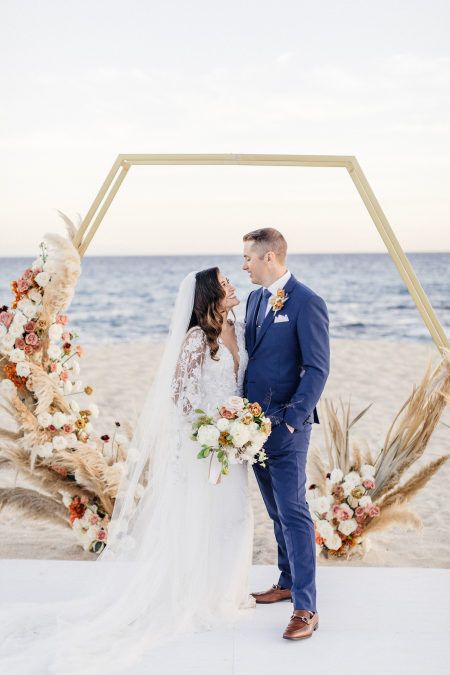 a luxurious hexagon wedding arch decorated with blusha nd dusty pink blooms, white flowers and pampas grass for an oceanfrotn ceremony