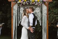 18 a bright boho summer wedding arch with macrame and lush blooms in pink, lilac and yellow on top