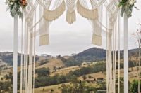 19 a bright macrame wedding arch with pink and blush blooms and greenery on the corners