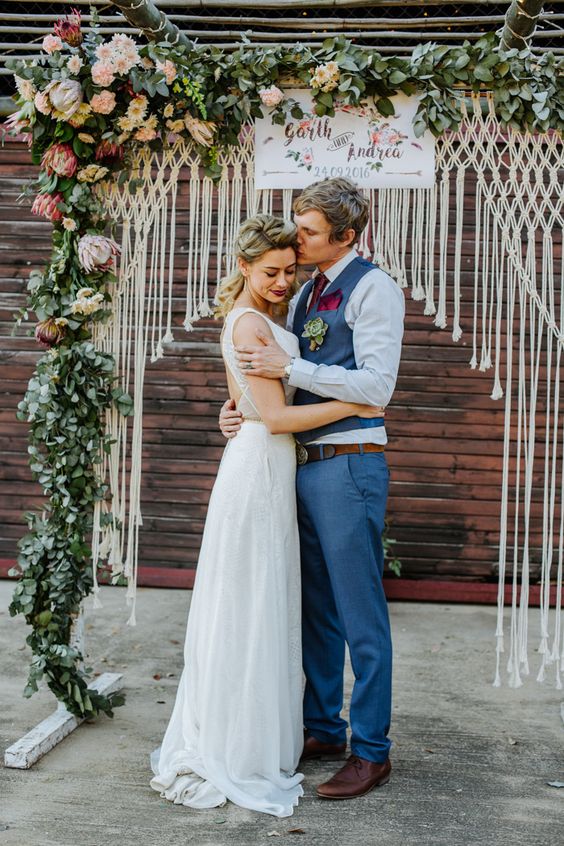 a bright summer wedding arch with macrame, lush greenery, pink, blush and fuchsia blooms