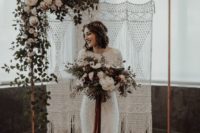 21 a copper wedding arch with a macrame hanging, some foliage and white blooms on one corner