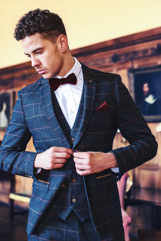 a navy windowpane print three piece suit, a white shirt, a burgundy velvet bow tie and a matching handkerchief