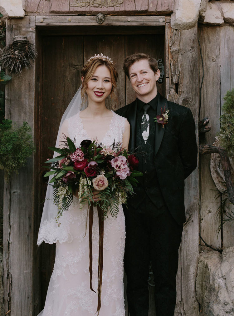 a black floral print three-piece suit, a matching printed white tie and a dark floral boutonniere for a Halloween groom