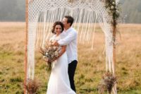 22 a fall boho wedding arch with macrame, some dried leaves and herbs plus white blooms, candles and dried herb arrangements