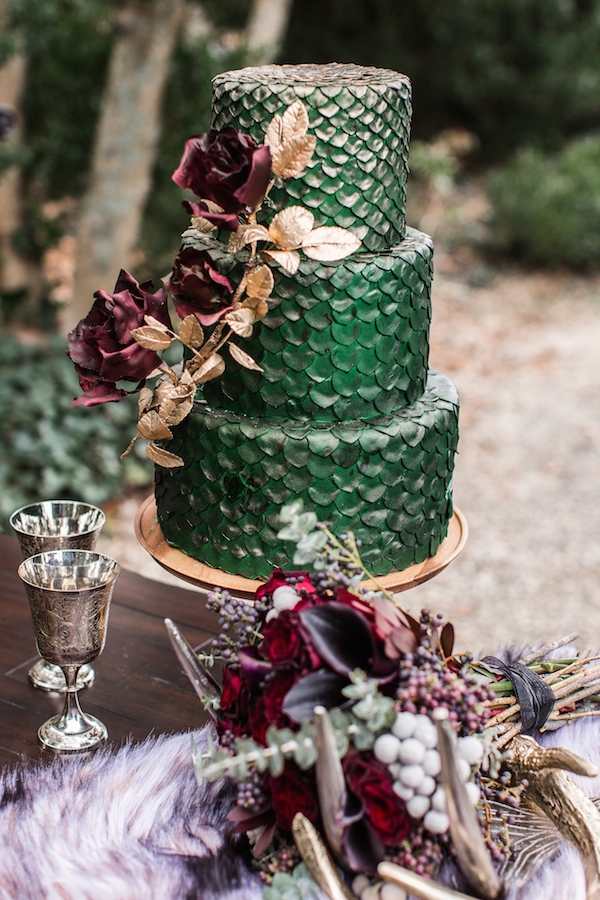a fantastic green dragon scale wedding cake with sugar red roses and gilded greenery is a very elegant idea