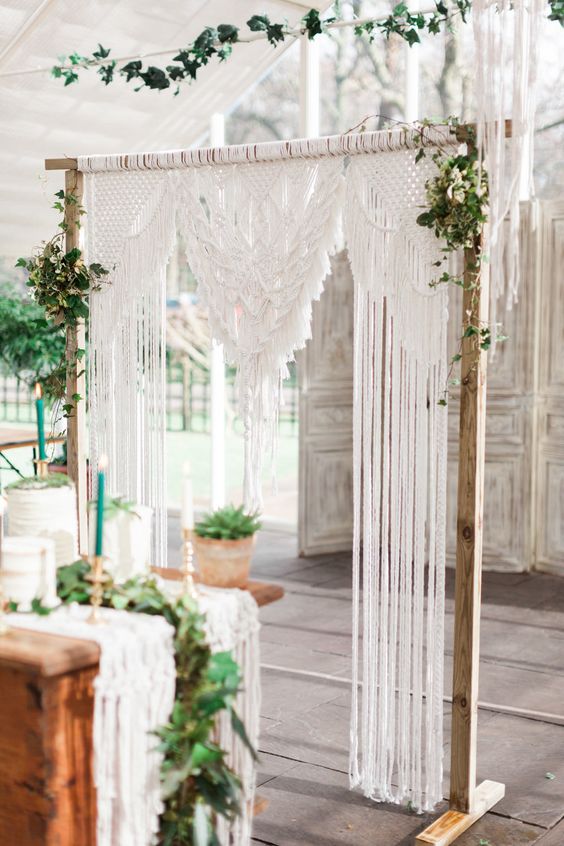 a simple and chic macrame wedding arch with some greenery on each corner is a cool idea