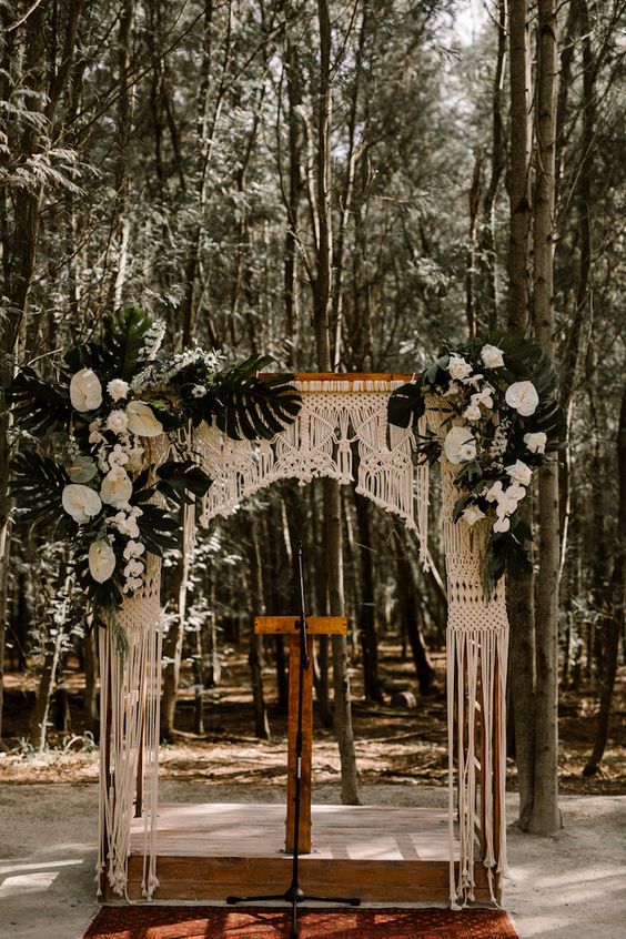 a tropical wedding arch with macrame, lush white tropical blooms and tropical leaves