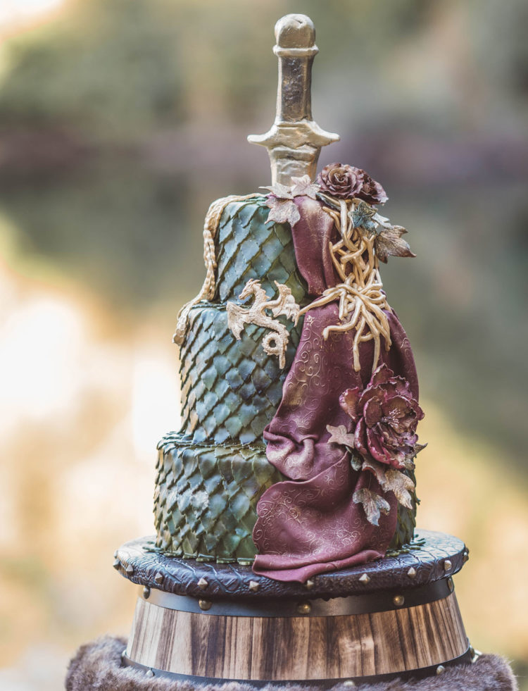 a unique wedding cake imitating green dragon scale, gilded dragons, a sword, sugar blooms looks very GOTH like