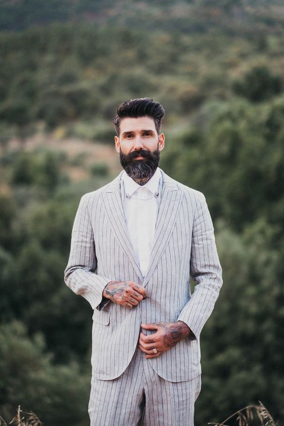a relaxed boho groom look with a neutral striped linen suit and a white shirt for a hot day