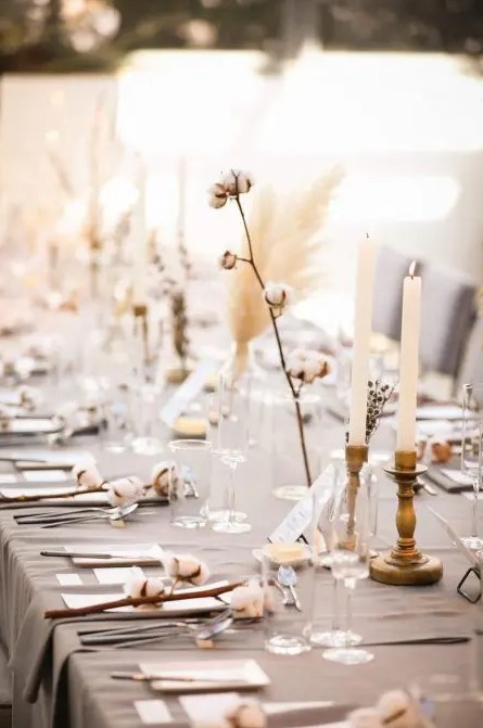 a beautiful neutral winter wedding tablescape with a grey tablecloth, cotton, dried blooms, candles and grass is awesome