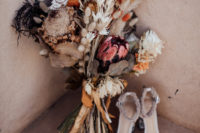 a beautiful wedding bouquet with dried grasses and blooms plus fresh blooms and rust ribbons is very eye-catchy