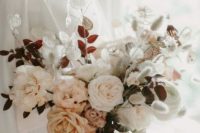 a delicate and soft wedding bouquet featuring dried lunaria, grasses and garden roses, leaves and rust-colored ribbons
