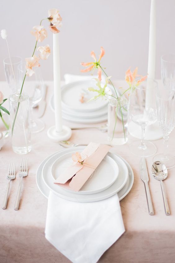 a delicate minimal cluster wedding centerpiece of glasses and peachy blooms is a cool idea for a spring wedding