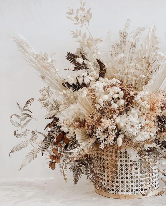 a gorgeous dried floral arrangement in a cane jar, dried leaves, herbs, flowers and branches for a textural look