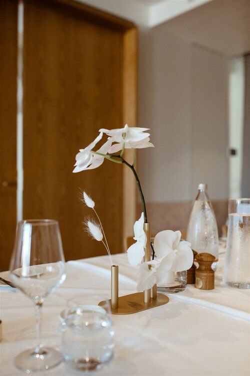 a lovely minimalist wedding centerpiece of gold bud vases with white orchids and grasses is a cool minimal idea