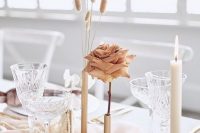 a minimalist cluster wedding centerpiece of gold bud vases, a coffee-colored rose, grasses, lunaria and a candle