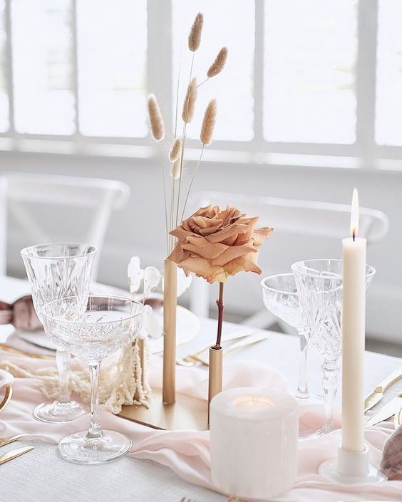 A minimalist cluster wedding centerpiece of gold bud vases, a coffee colored rose, grasses, lunaria and a candle