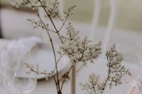 a minimalist wedding centerpiece of tall and thin vases and some blooming branches is a cool idea for a minimal wedding