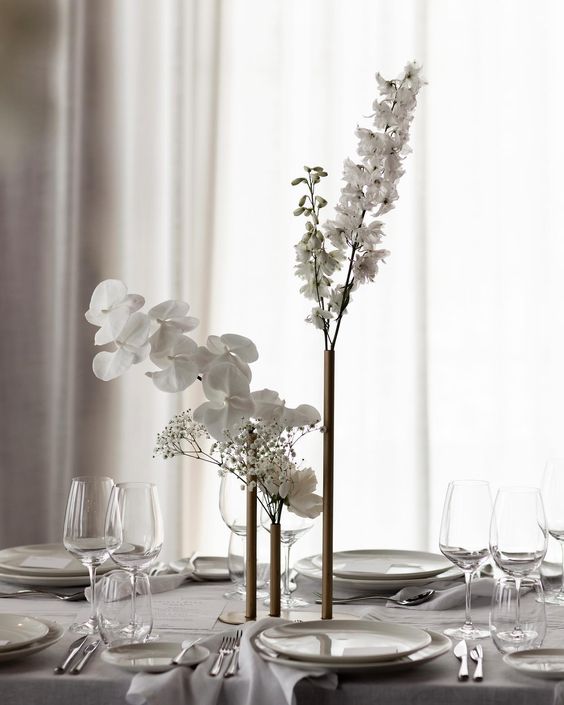 a minimalist wedding centerpiece of tall and thin vases with some white blooms is a lovely idea for a minimal wedding
