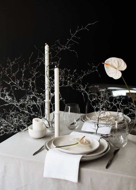 a minimalist wedding centerpiece of white anthuriums, white candles and whitewashed branches is amazing
