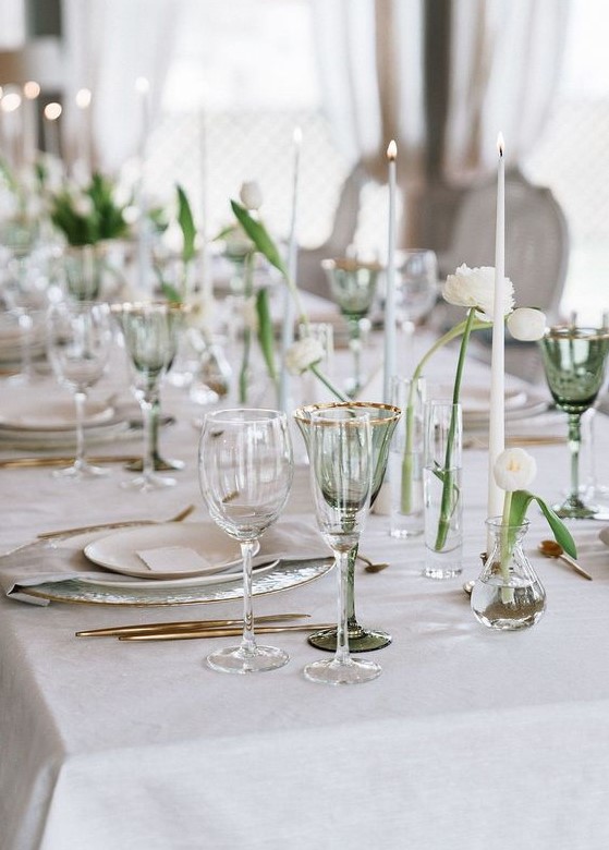 a refined and minimal Scandinavian tablescape with white candles, cluster centerpieces with white blooms, neutral porcelain