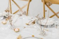 a refined white winter wedding tablescape with grey plates, gold touches, dried blooms, white linens is very stylish
