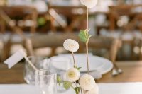 a simple minimalist wedding centerpiece of white mums in a glass vases and some candles is a cool idea for a minimal wedding