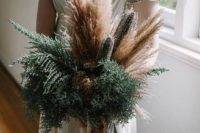 a stylish wedding bouquet done of wheat, pampas grass, ferns and dried blooms features much texture