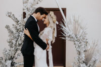 a triangle wedding arch doen in white, with silver eucalyptus and palm leaves is a real out-of-this world idea