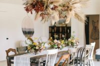 an overhead floating arrangement of pampas grass, dried leaves and fronds plus bright burgundy foliage
