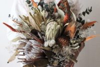 an oversized wedding bouquet with dried blooms and foliage, fresh greenery and blooms shows off much texture