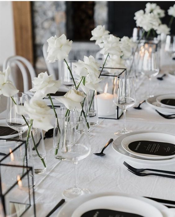 elegant minimalist wedding centerpieces of white roses, candle lanterns and white porcelain and black menues for a minimal wedding