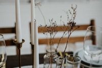 minimalist wedding centerpieces of clear vases with dried grasses and tall and thin candles in brass candleholders