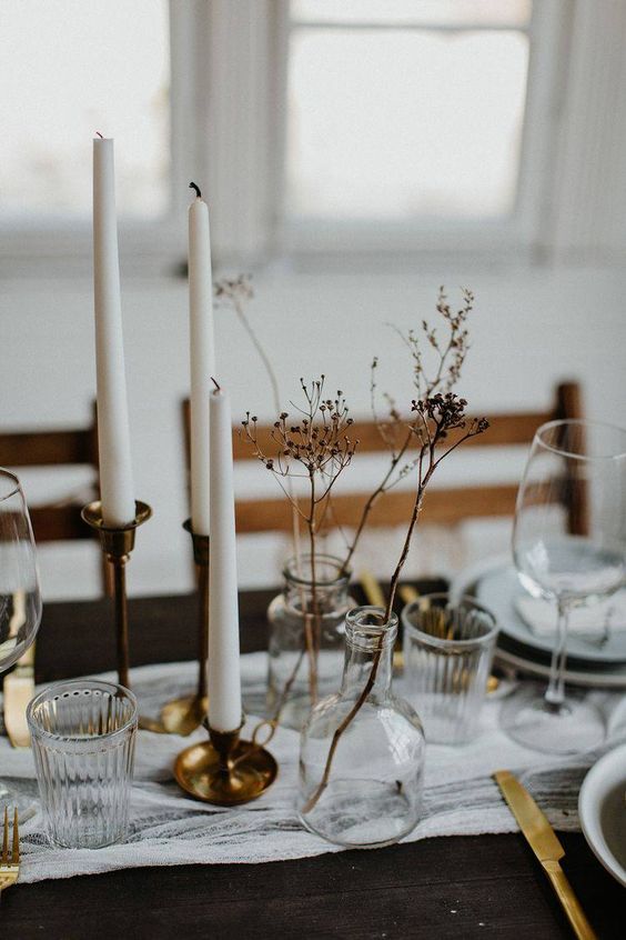 minimalist wedding centerpieces of clear vases with dried grasses and tall and thin candles in brass candleholders