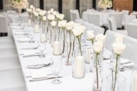 minimalist wedding centerpieces of single white roses in glasses and pillar candles are amazing for a minimalist wedding