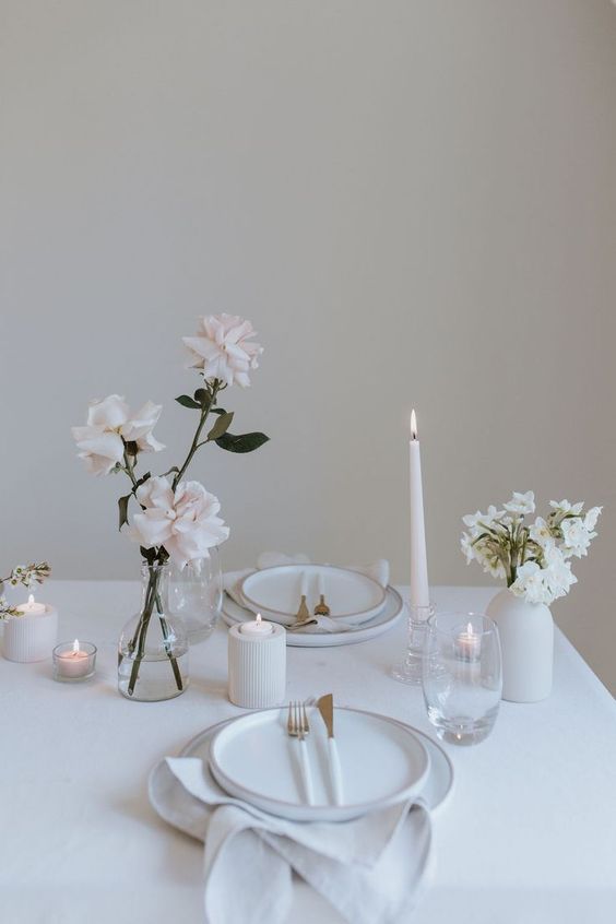 pretty minimalist wedding centerpieces of a clear glass vase with blush roses and a white vase with white blooms