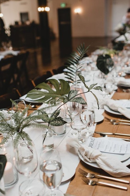 simple clear glasses and vases with statement foliage and greenery make the table look fresh and stylish