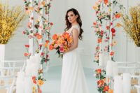 02 a bright modern wedding aisle done with white chairs, colorful blooms in orange and rust, candles on tall stands