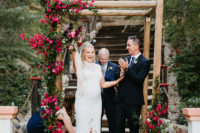 05 The groom was wearing a black suit with a navy tie and brown shoes, and the wedding arch was decorated with bougainvilleas