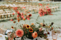 The wedding tablescape was done with rust, orange, red blooms and teal napkins