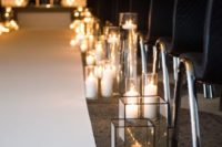 07 a simple and chic modern wedding aisle with black chairs, geometric lanterns and just candles on the floor