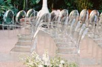 09 clear ghost chairs and a lush greenery and white bloom arrangement for a beautiful modern outdoor wedding aisle