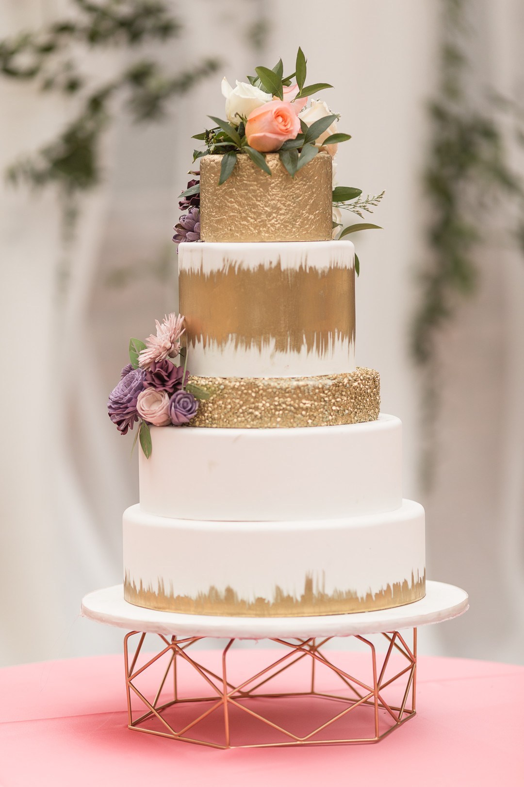 The wedding cake was done in white and gold, topped with fresh blooms and greenery plus a copper stand